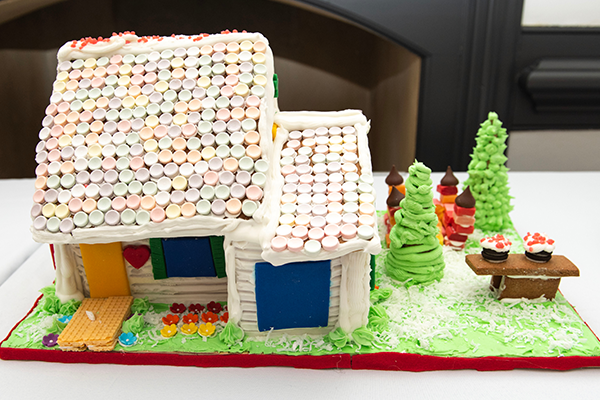 A gingerbread house with an attached garage. The building has white frosting siding, and a steep smartie-shingled roof. A sugar wafer walkway leads to the front door, and the starburst bouncy house in the side yard is perfect for kids to play on.