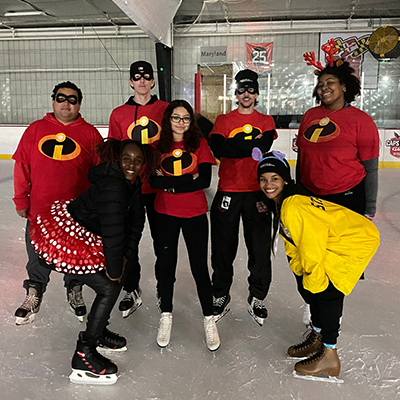 A group all dressed up like the Incredibles posing while ice skating