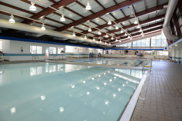 Indoor swimming pool facility with lanes, lifeguard chairs, and natural light coming through large windows at Allentown Splash, Tennis, and Fitness Park.