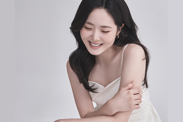 Promotional headshot of a smiling woman wearing an ivory gown.