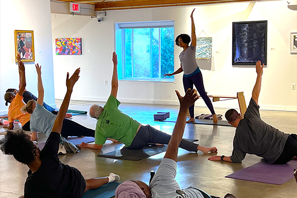 An instructor leads a yoga class in an art gallery.