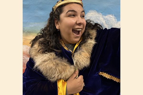 A performer wears an elaborate, velvet cloak with a fur collar.